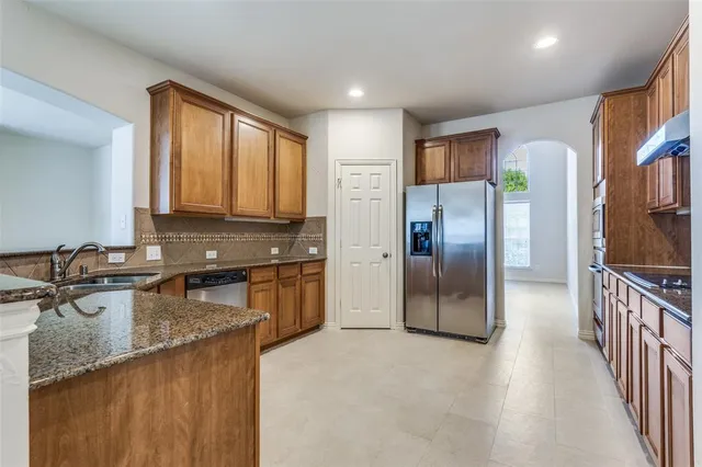 a kitchen with stainless steel appliances granite countertop a refrigerator and a sink