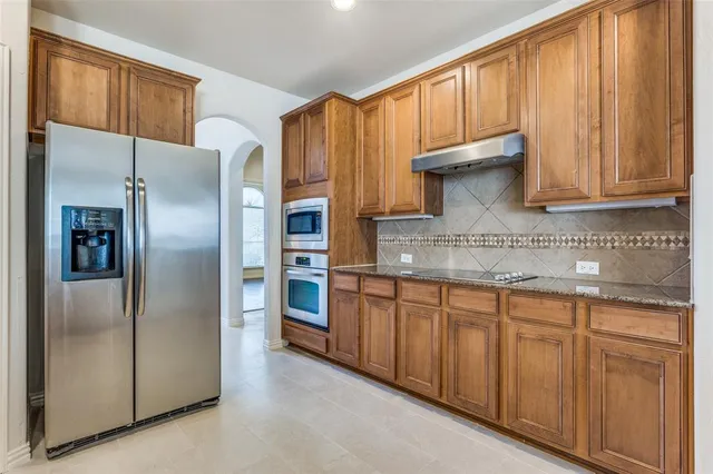 a kitchen with stainless steel appliances granite countertop a refrigerator and a sink