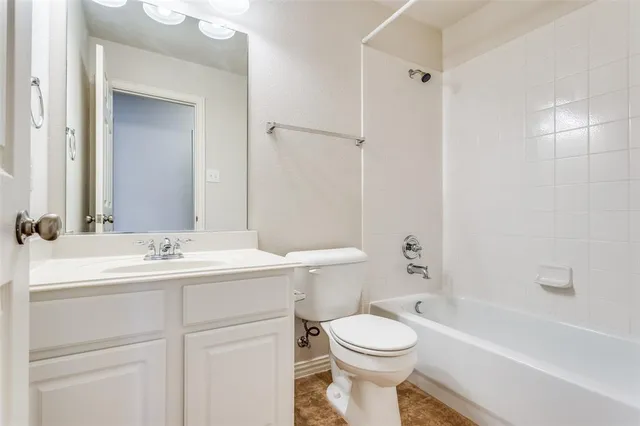 a bathroom with a toilet a sink a mirror a bathtub and vanity