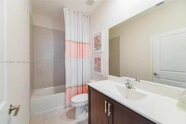 a bathroom with a bathtub shower sink vanity mirror and toilet