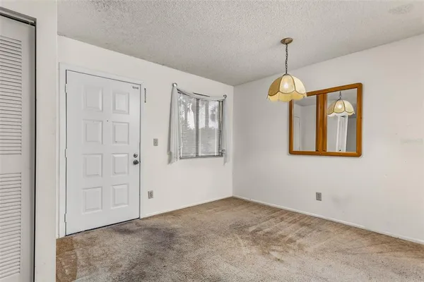 a view of an empty room with window and chandelier fan