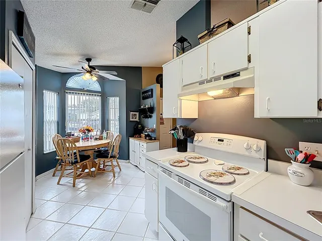 a kitchen filled with a white stove top oven a sink dishwasher and white cabinets with wooden floor