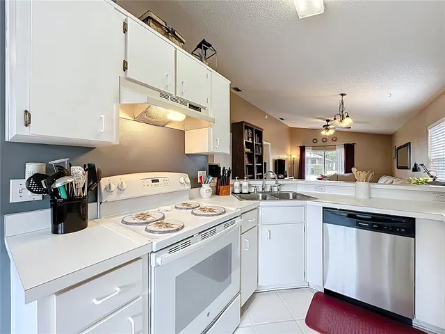 a kitchen with a sink dishwasher stove and white cabinets
