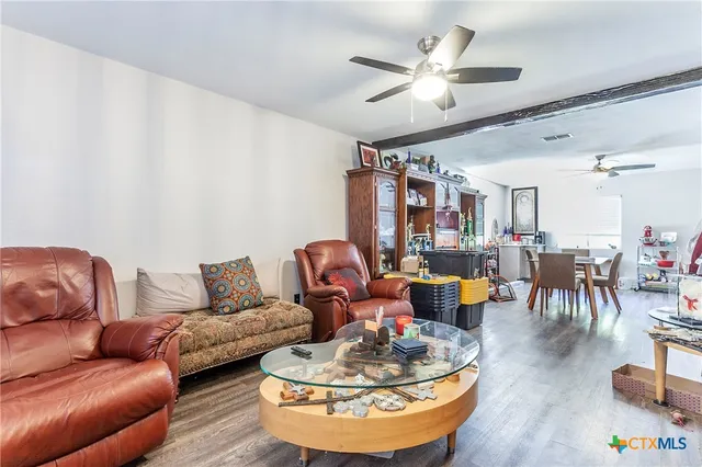 a living room with furniture kitchen view and a chandelier