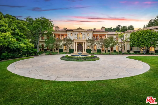a view of a white house with a big yard plants and large trees