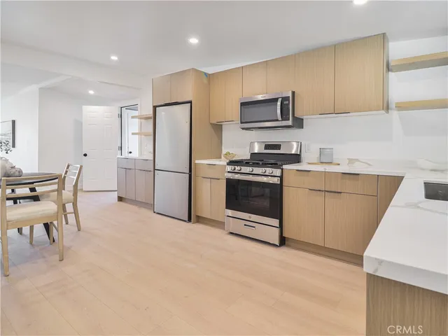 a kitchen with stainless steel appliances granite countertop a stove top oven a sink refrigerator and a refrigerator with wooden floor