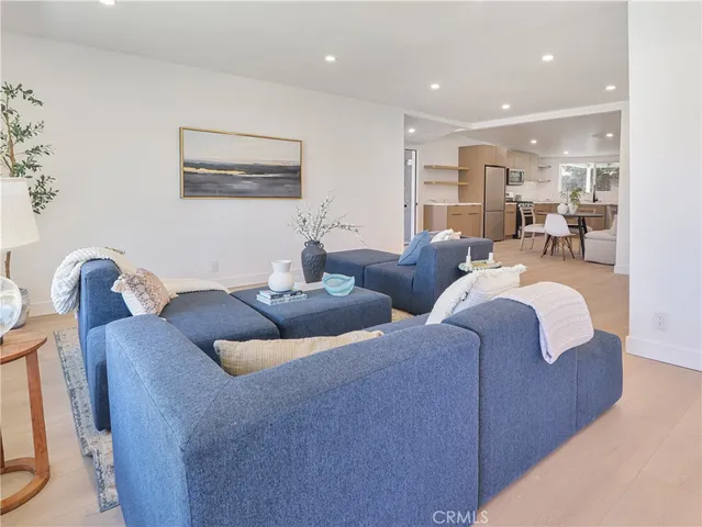 a living room with couches and kitchen view with wooden floor