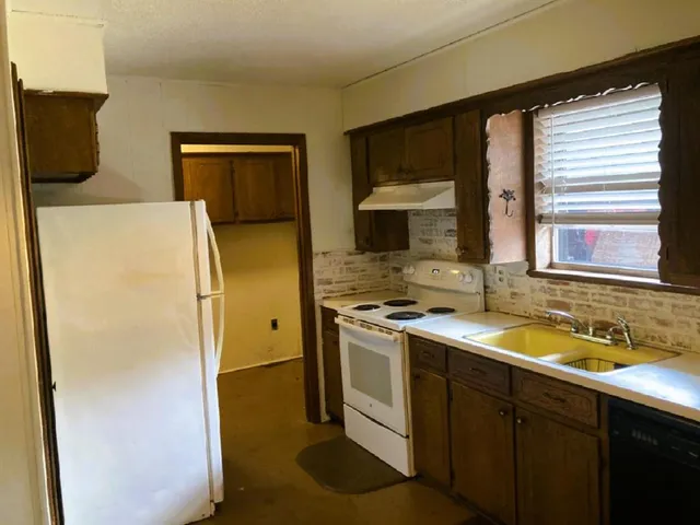 a kitchen with a sink a refrigerator and a stove top oven