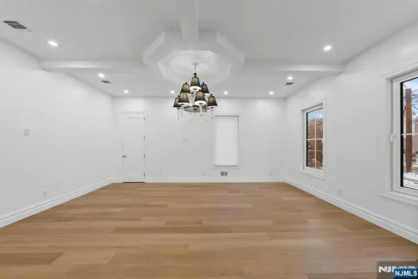 an empty room with windows and chandelier fan