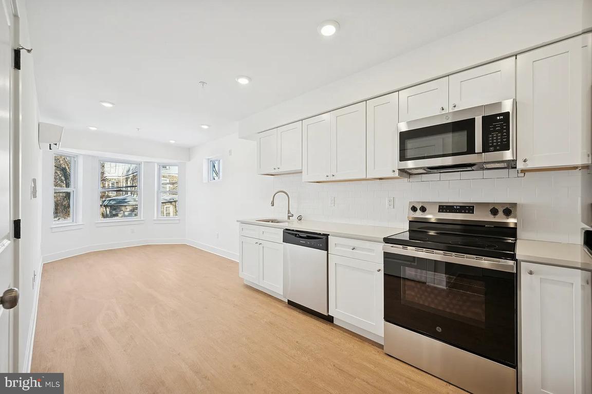 3413 North 19th Street, Unit 2F Philadelphia, PA 19140 - Photo 8 of 24 a kitchen with stainless steel appliances granite countertop a stove top oven a sink and a microwave