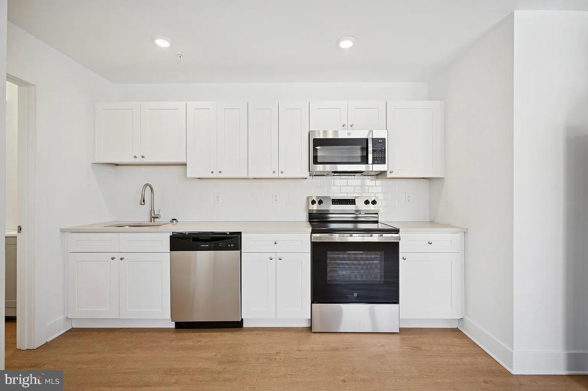 3413 North 19th Street, Unit 2F Philadelphia, PA 19140 - Photo 10 of 24 a kitchen with stainless steel appliances a stove a sink a microwave and cabinets