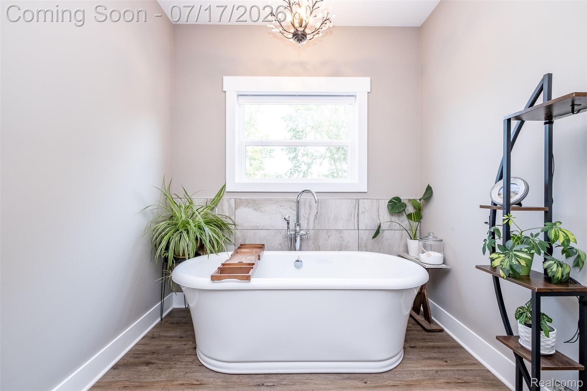 12349 Sugar Maple Drive Fenton, MI 48430 - Photo 26 of 67 Freestanding soaking tub with a wall-mounted faucet, wood-finish flooring, and a decorative ceiling fixture