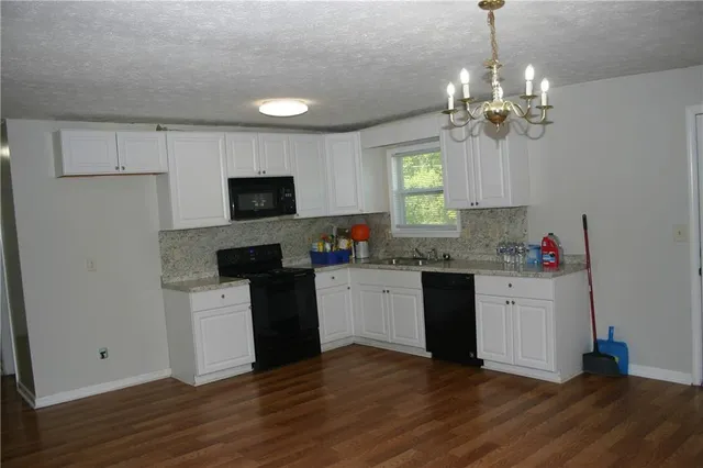 a kitchen with granite countertop a stove cabinets and wooden floor