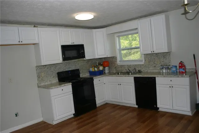 a kitchen with granite countertop a stove a sink and a microwave