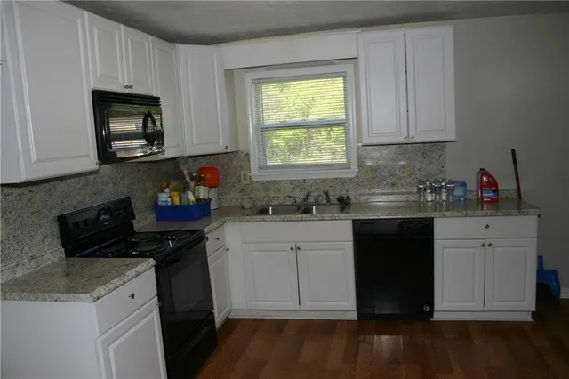 a kitchen with granite countertop white cabinets and black appliances