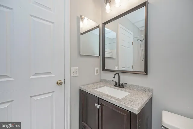 a bathroom with a granite countertop sink a toilet and a mirror