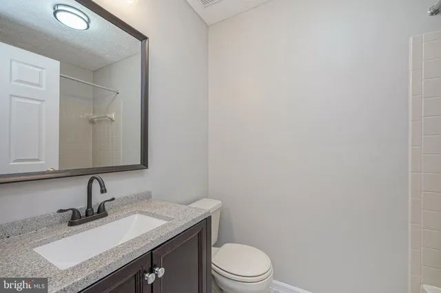 a bathroom with a granite countertop sink toilet a mirror and vanity