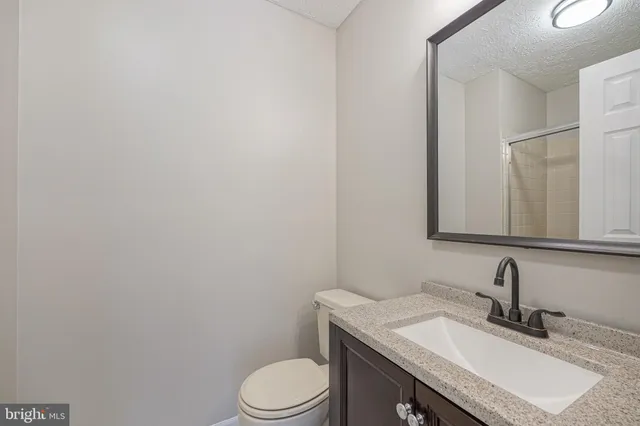 a bathroom with a granite countertop toilet sink and mirror
