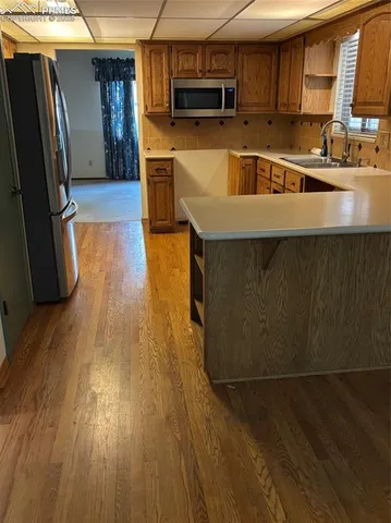 a kitchen with stainless steel appliances a stove a refrigerator a sink a stove wooden floor and cabinets