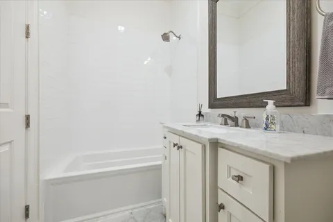 a bathroom with a granite countertop sink a mirror and a bathtub