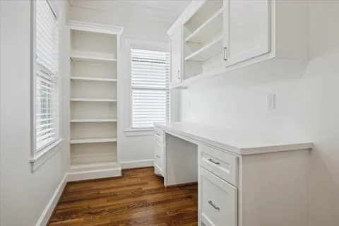 a kitchen with white cabinets and wooden floor