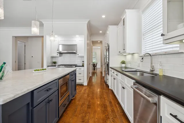 a large kitchen with a large counter top a sink stainless steel appliances and cabinets