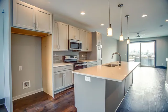 a kitchen with stainless steel appliances granite countertop a refrigerator a sink dishwasher a stove and white cabinets with wooden floor