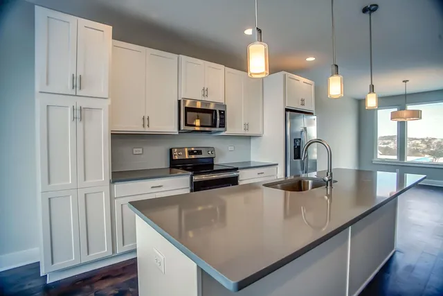 a kitchen with stainless steel appliances granite countertop a sink a stove a refrigerator a center island and cabinets