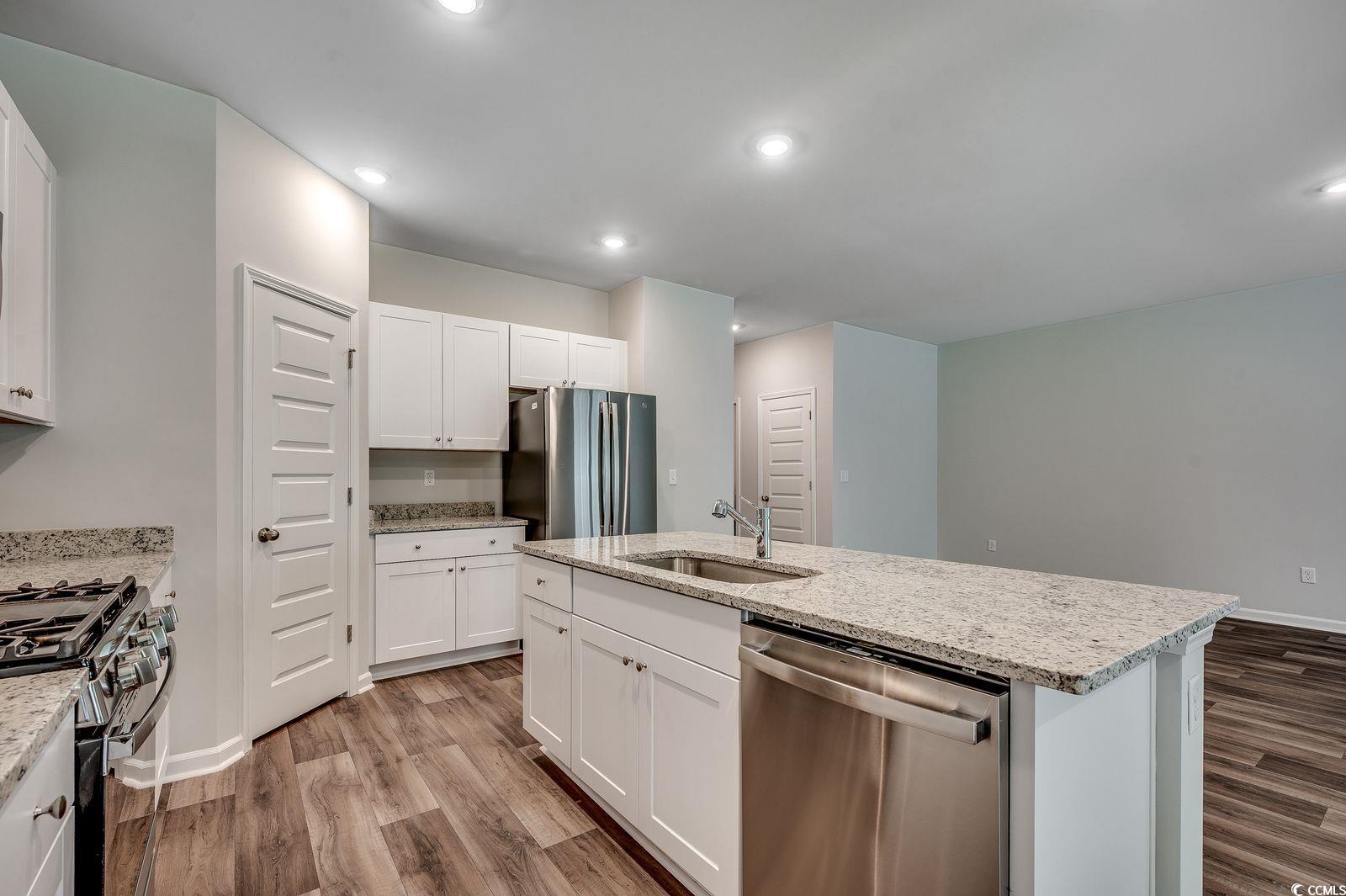1004 Sentinel Court Little River, SC 29566 - Photo 6 of 31 Kitchen with appliances with stainless steel finishes, white cabinets, light stone counters, light wood-style floors, and recessed lighting