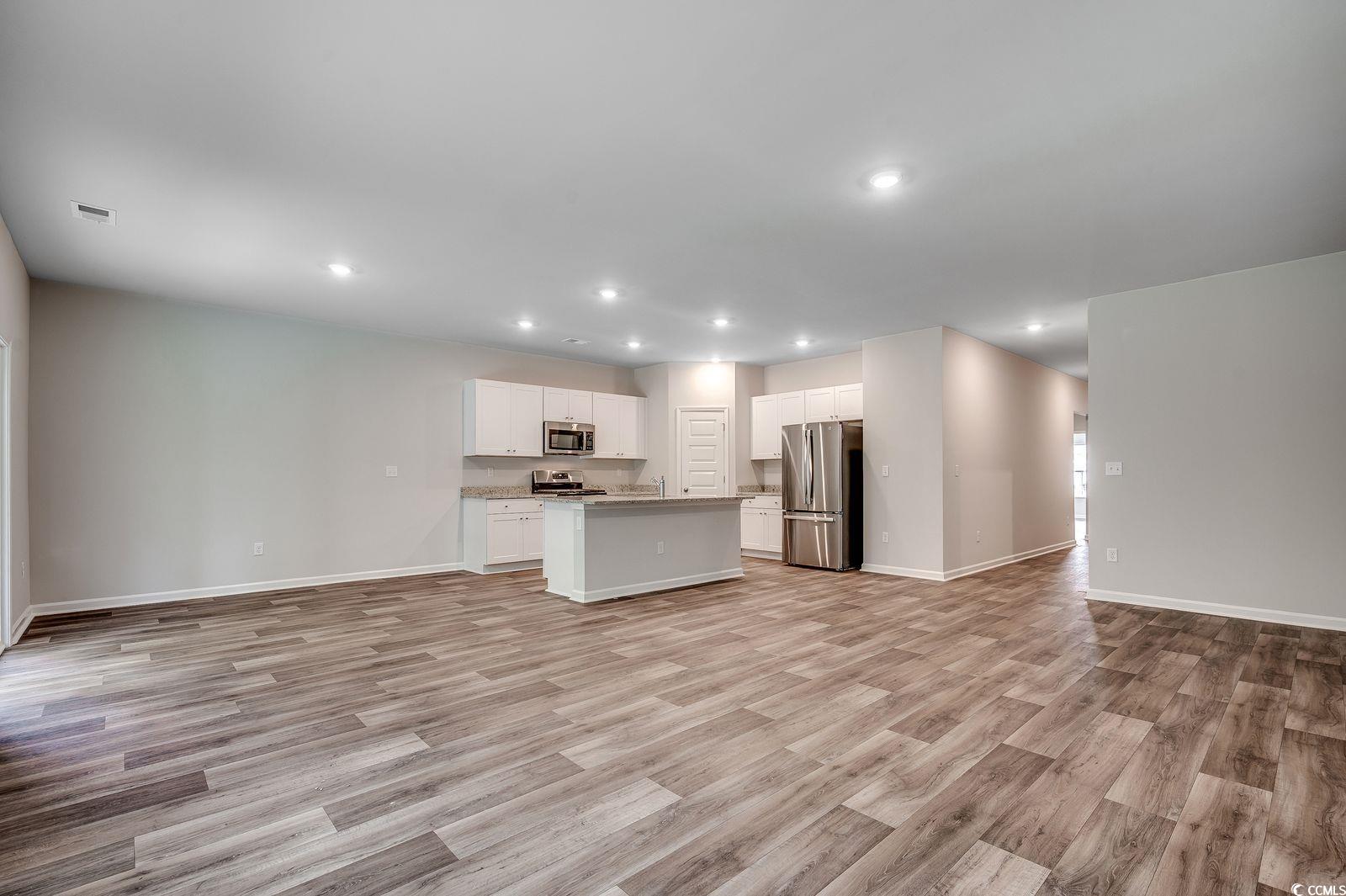 1004 Sentinel Court Little River, SC 29566 - Photo 30 of 31 Kitchen featuring open floor plan, appliances with stainless steel finishes, white cabinets, a center island with sink, and light wood-style flooring