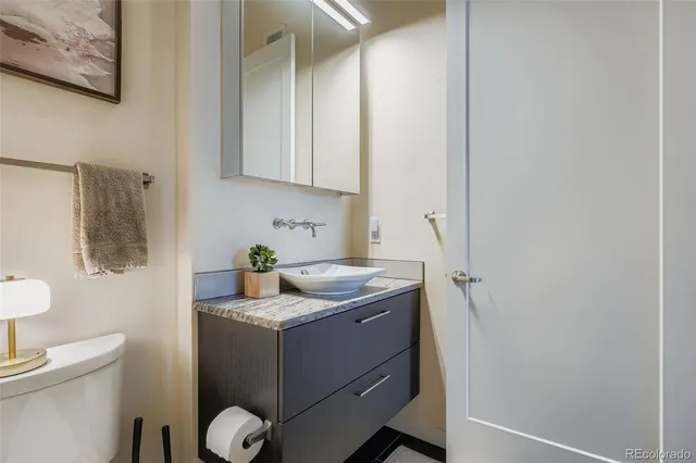 a bathroom with a granite countertop sink a toilet and a mirror