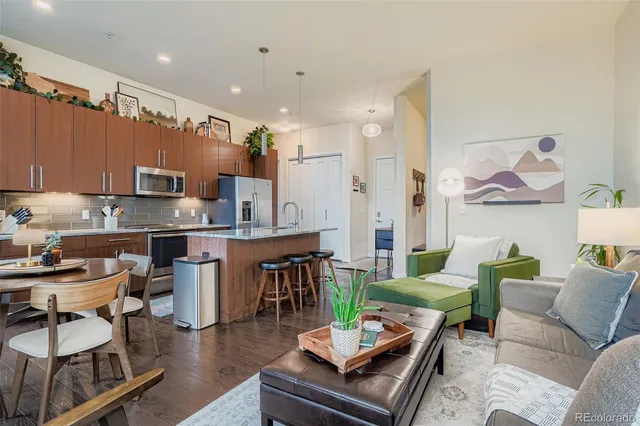 a living room with furniture a rug kitchen view and a table