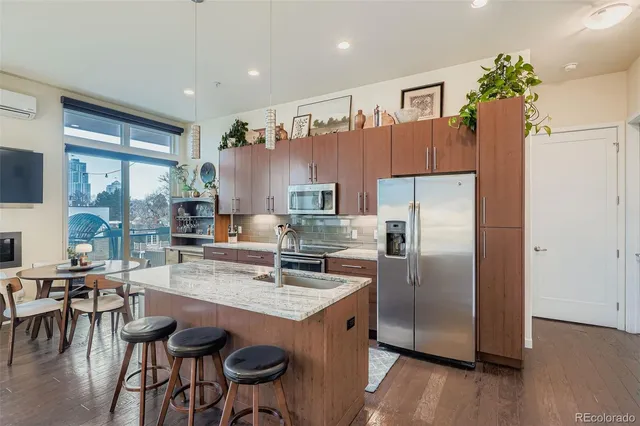 a kitchen with stainless steel appliances granite countertop a refrigerator a sink a stove and chairs