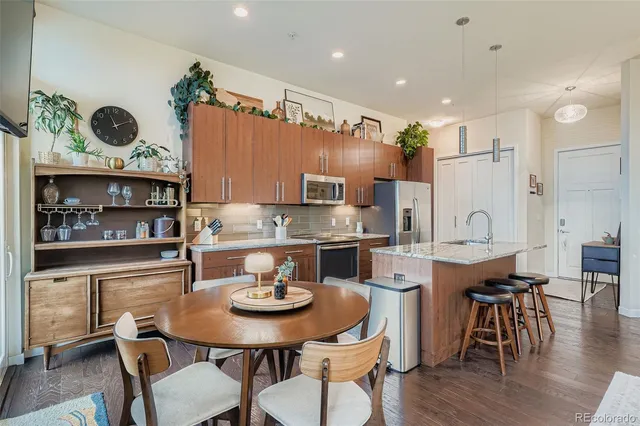 a kitchen with stainless steel appliances kitchen island granite countertop a dining table chairs and white cabinets