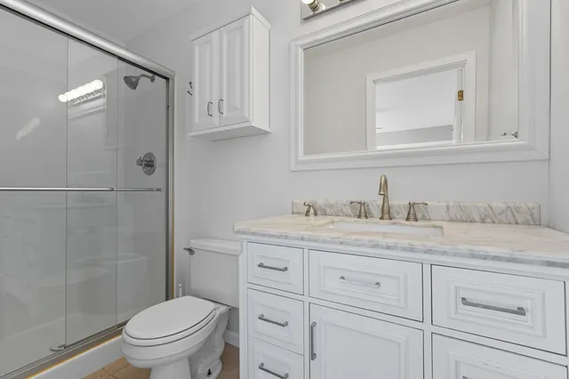a bathroom with a granite countertop sink toilet and shower