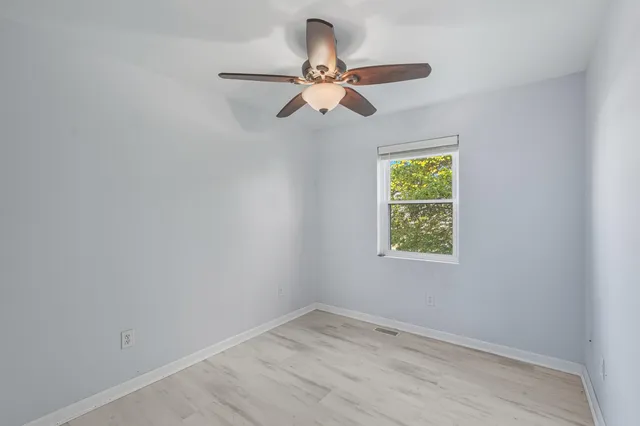 an empty room with a window and a fan