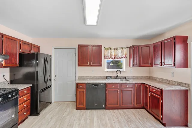 a kitchen with stainless steel appliances granite countertop a stove a sink dishwasher a refrigerator and wooden cabinets