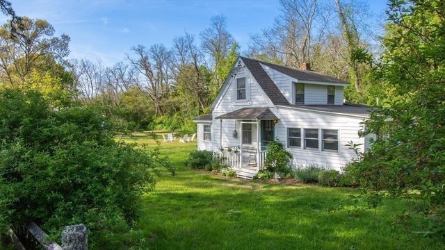 a view of a house with a big yard potted plants and large tree