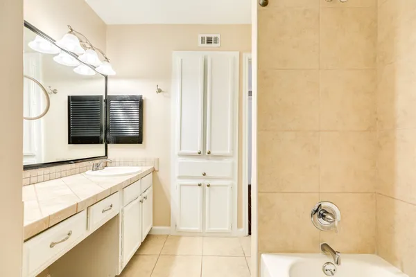 a spacious bathroom with a tub sink and mirror