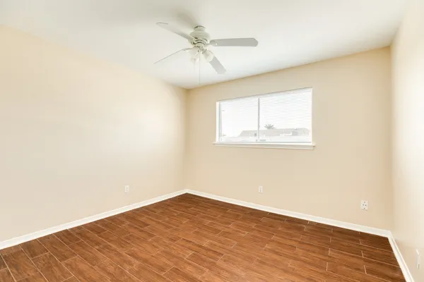 an empty room with wooden floor fan and windows