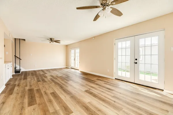 a view of empty room with wooden floor and fan