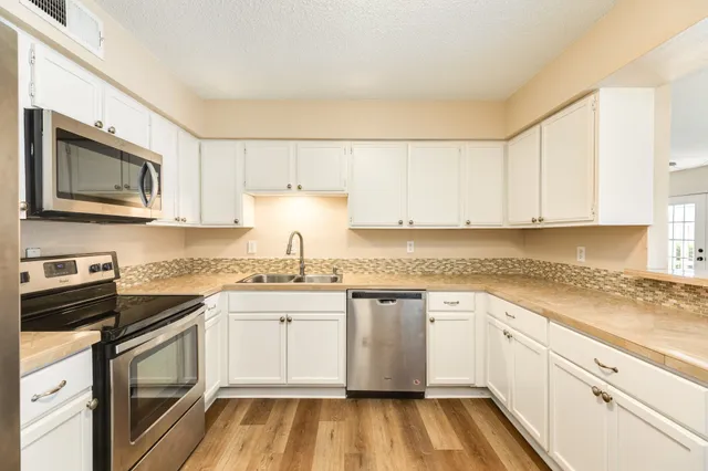 a white kitchen with granite countertop stainless steel appliances