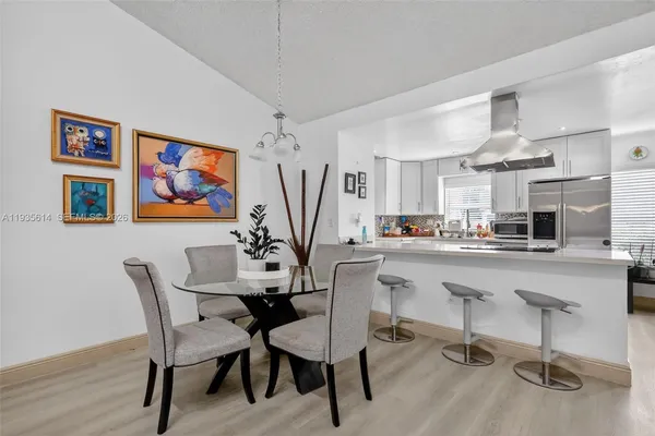 a kitchen with stainless steel appliances a dining table chairs and a refrigerator
