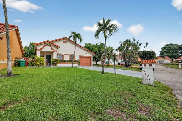a view of a white house with a big yard and palm trees