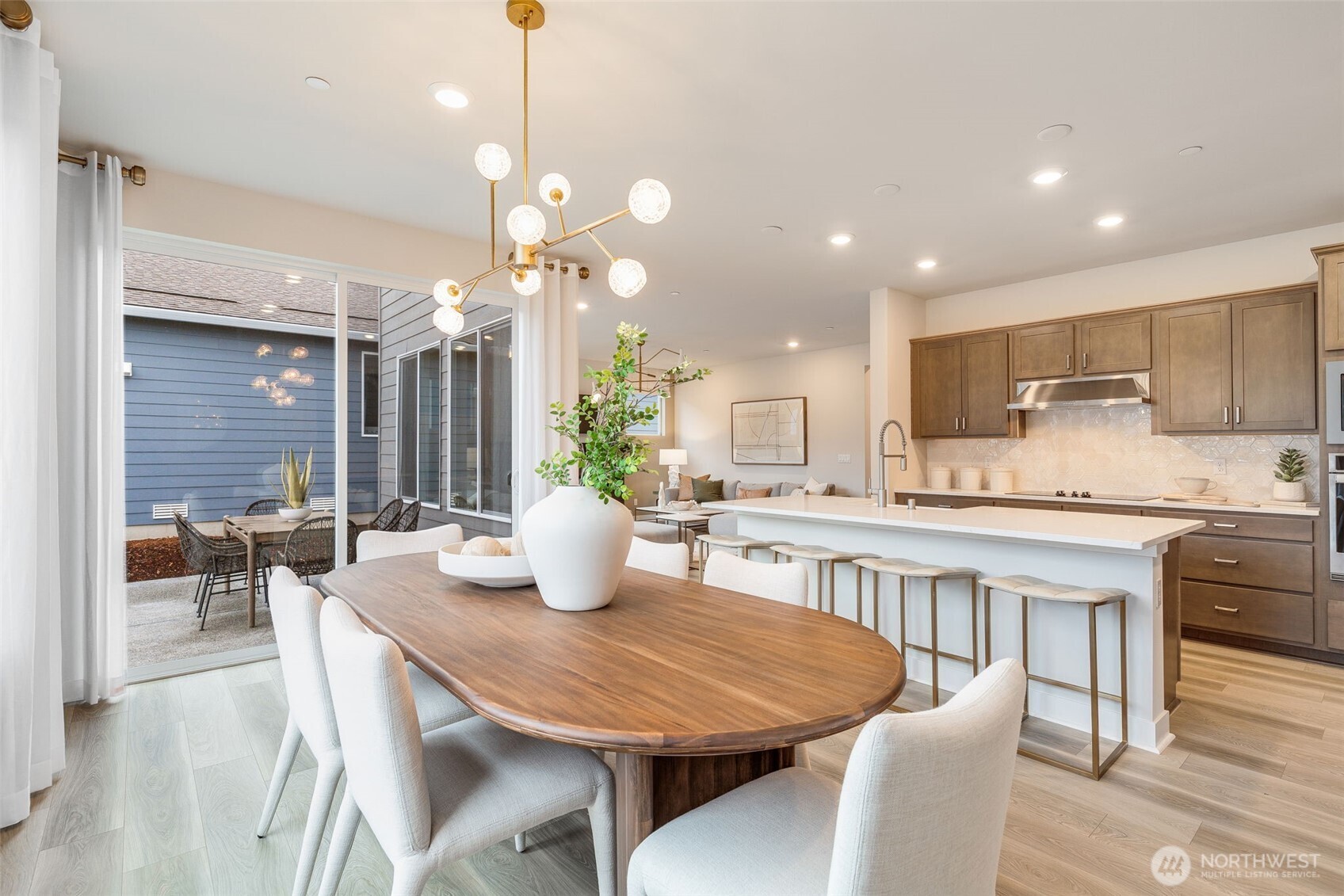 23338 Arbors Ter Road Northeast, Unit 201 Kingston, WA 98346 - Photo 6 of 17 a kitchen with kitchen island a dining table chairs and white cabinets