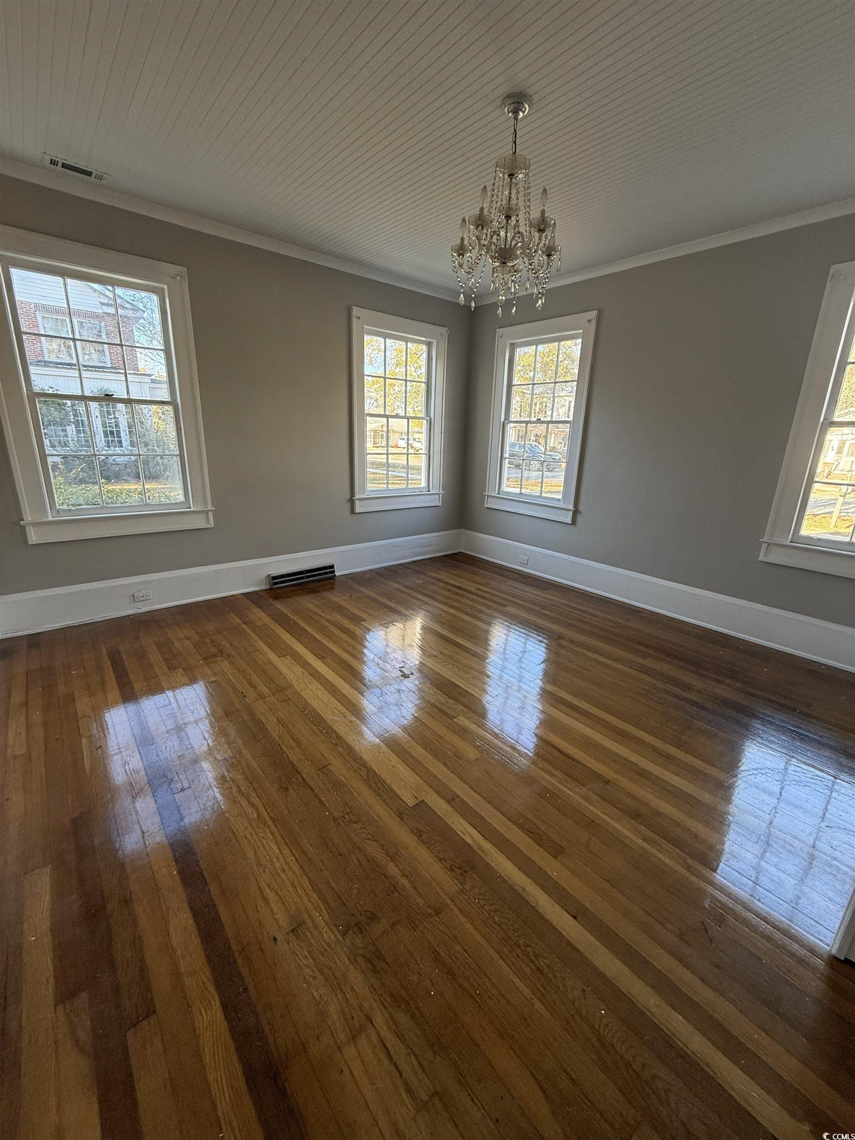 305 East Bamberg Street Latta, SC 29565 - Photo 6 of 13 Empty room with a chandelier, ornamental molding, dark wood finished floors, and wooden ceiling