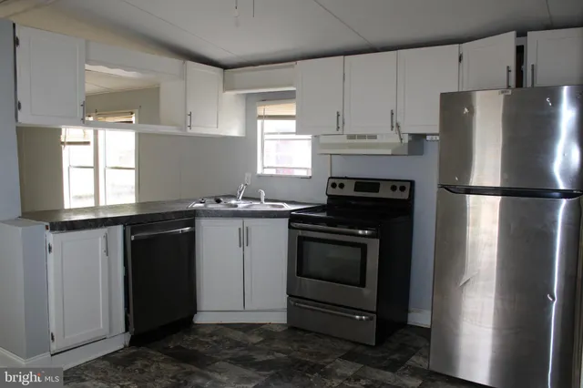 a view of a refrigerator in kitchen and empty room