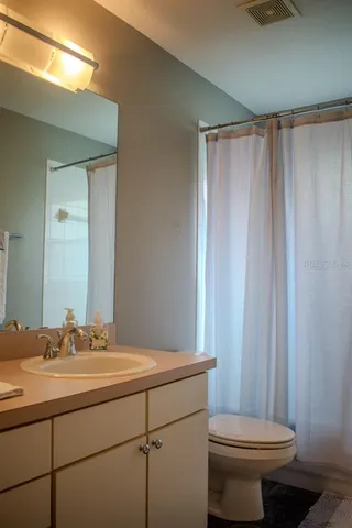 a bathroom with a sink a toilet a mirror and shower curtain