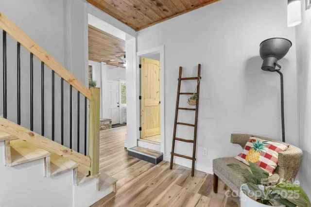 a view of a hallway to a livingroom with wooden floor and furniture