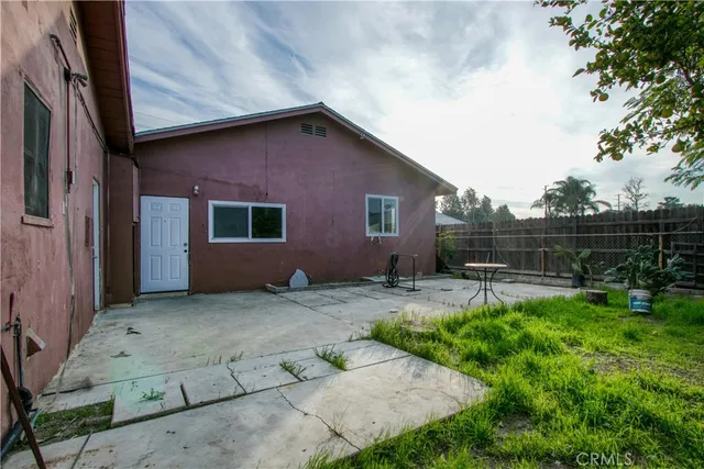 a backyard of a house with potted plants and large tree